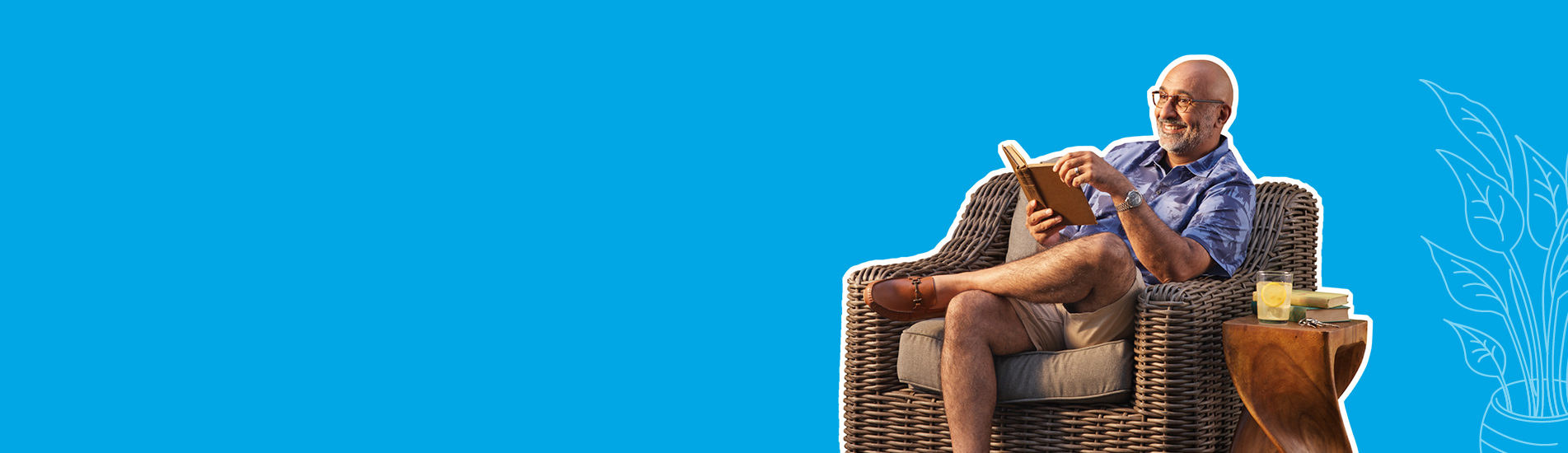 older well to do man smiling holding a book on his resort home patio